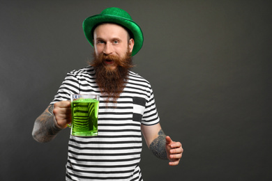Bearded man with green beer on grey background. St. Patrick's Day celebration