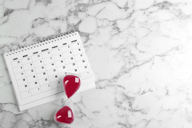 Photo of Calendar and hourglass on white marble background, flat lay. Space for text