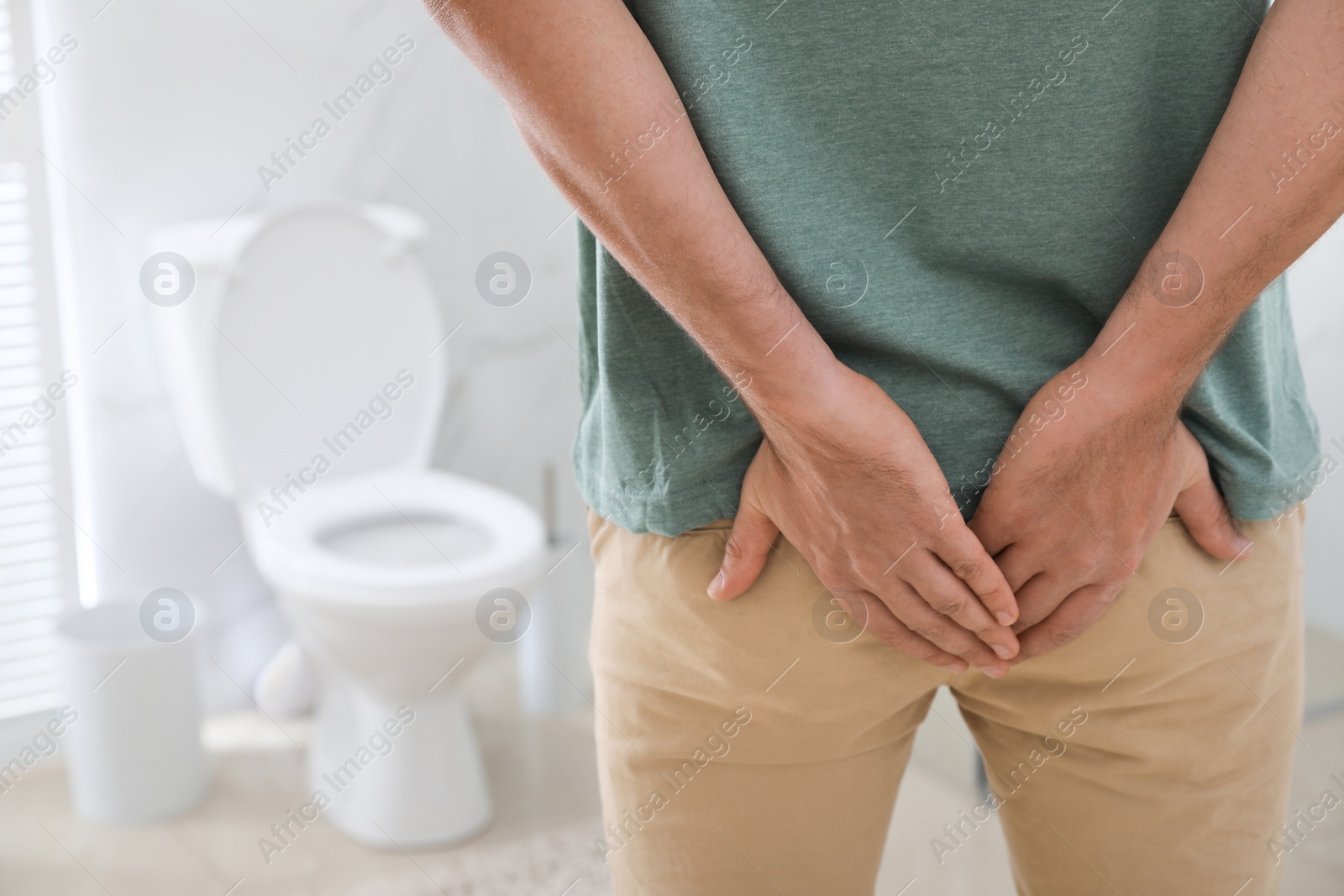 Photo of Man suffering from hemorrhoid in rest room, closeup