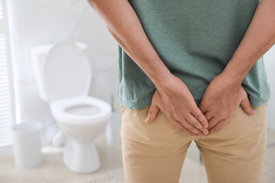 Photo of Man suffering from hemorrhoid in rest room, closeup