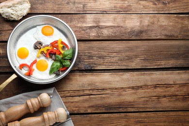 Photo of Tasty fried eggs with vegetables in pan and spice shakers on wooden table, flat lay. Space for text