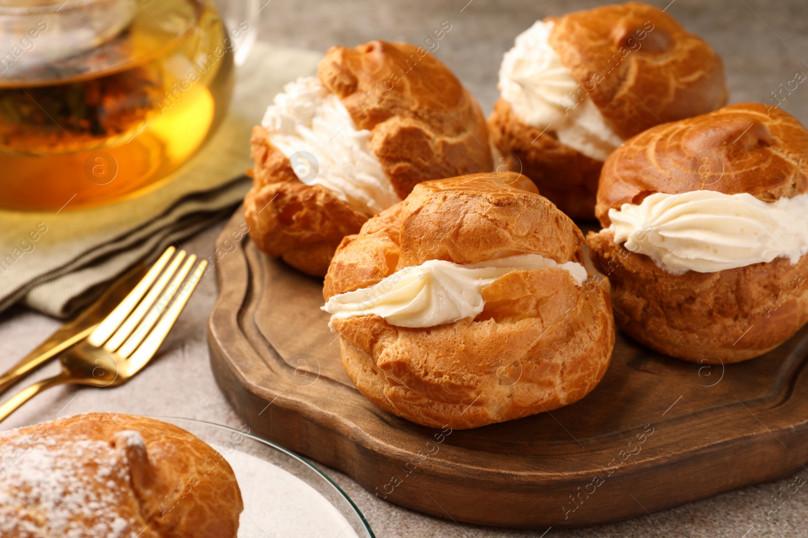 Photo of Delicious profiteroles filled with cream on grey table