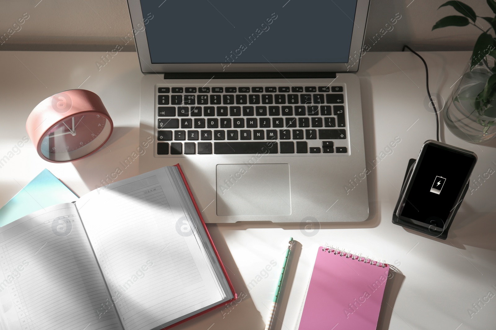 Photo of Modern workplace and smartphone charging with wireless pad, above view