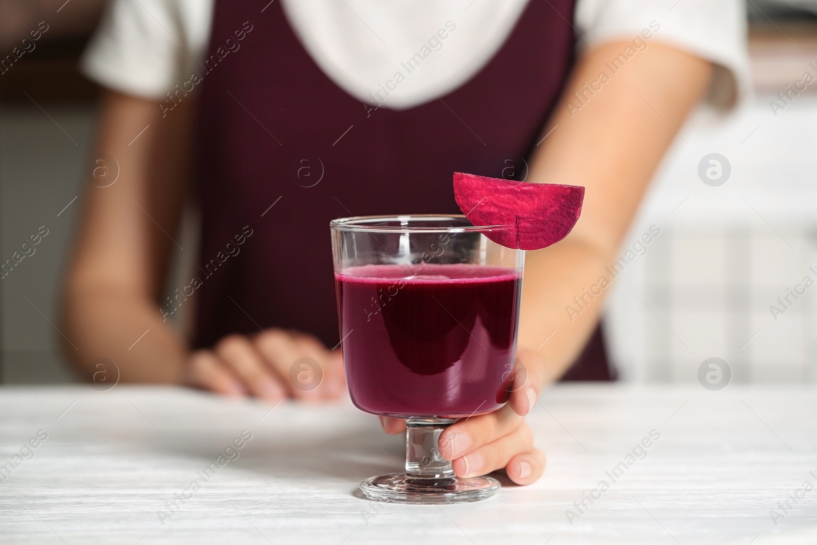 Photo of Woman with glass of beet smoothie at table, closeup