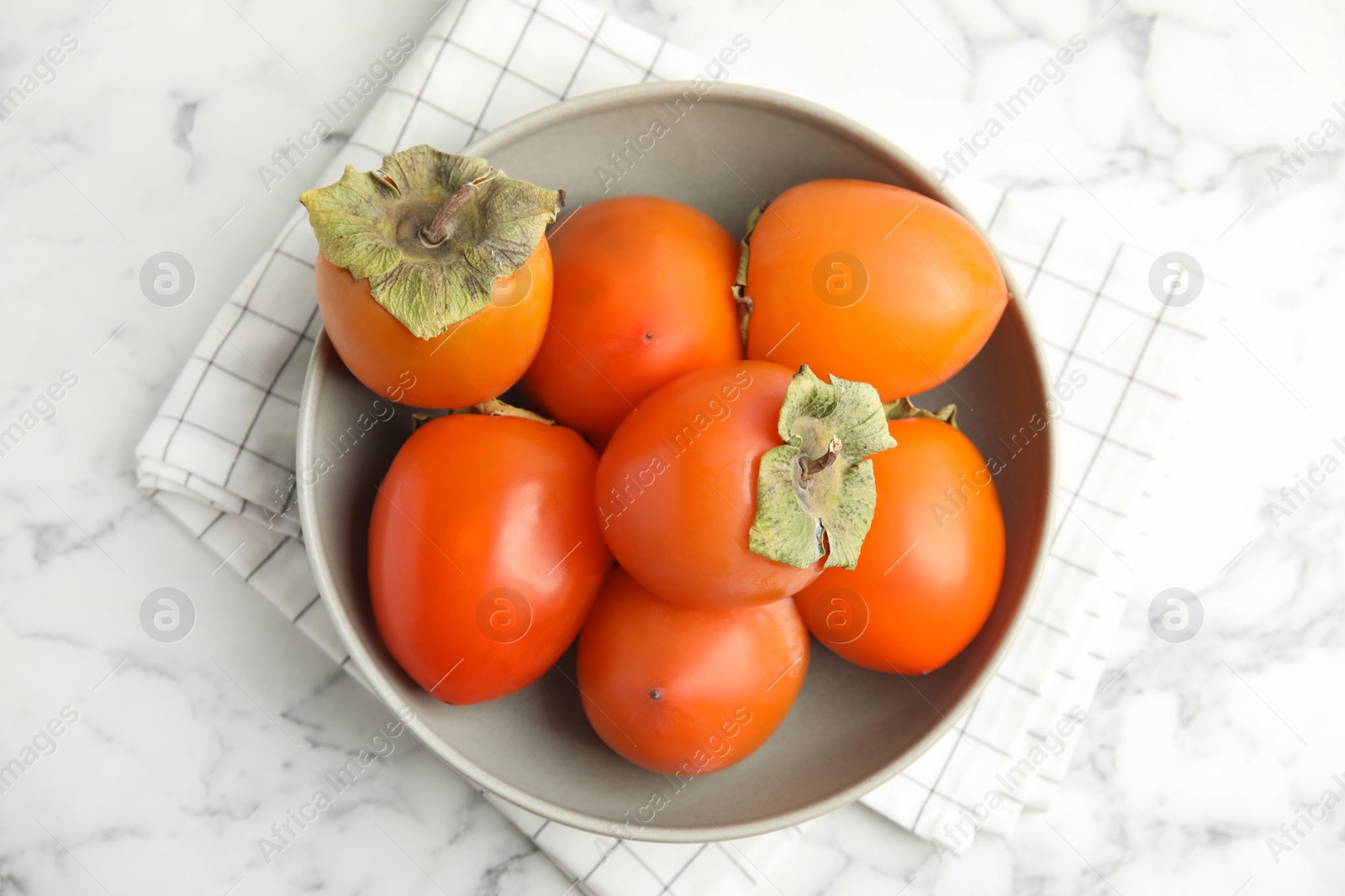 Photo of Tasty ripe persimmons on white marble table, flat lay