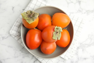 Photo of Tasty ripe persimmons on white marble table, flat lay