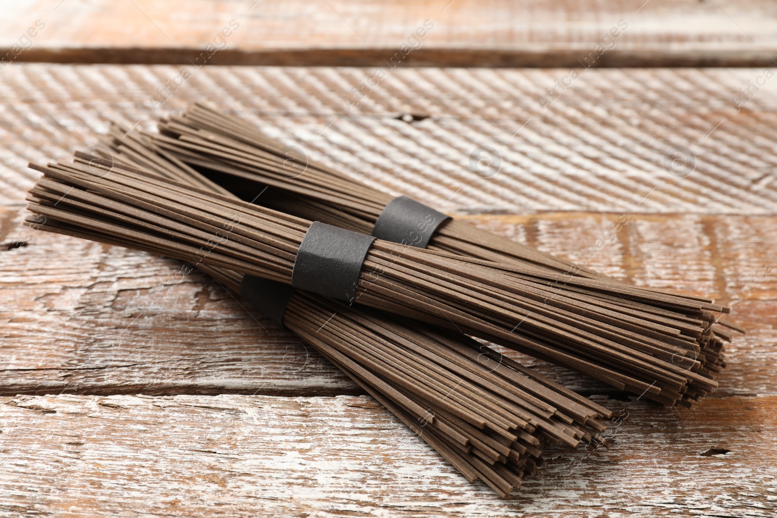 Photo of Uncooked buckwheat noodles (soba) on wooden table, closeup
