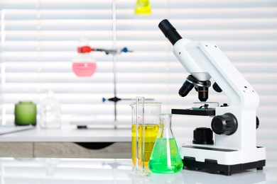 Laboratory analysis. Different glassware with liquids and microscope on white table indoors