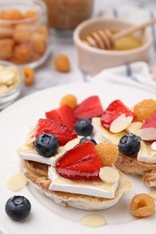 Tasty sandwiches with brie cheese, fresh berries and almond flakes on table, closeup