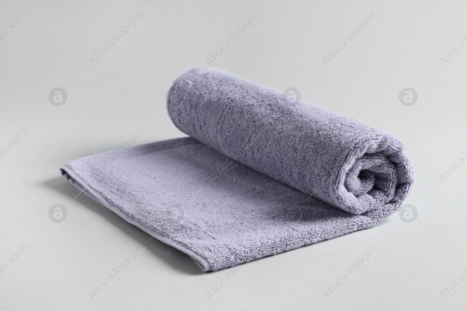 Photo of Fresh fluffy rolled towel on grey background