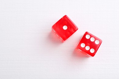 Photo of Two red game dices on white wooden table, flat lay. Space for text