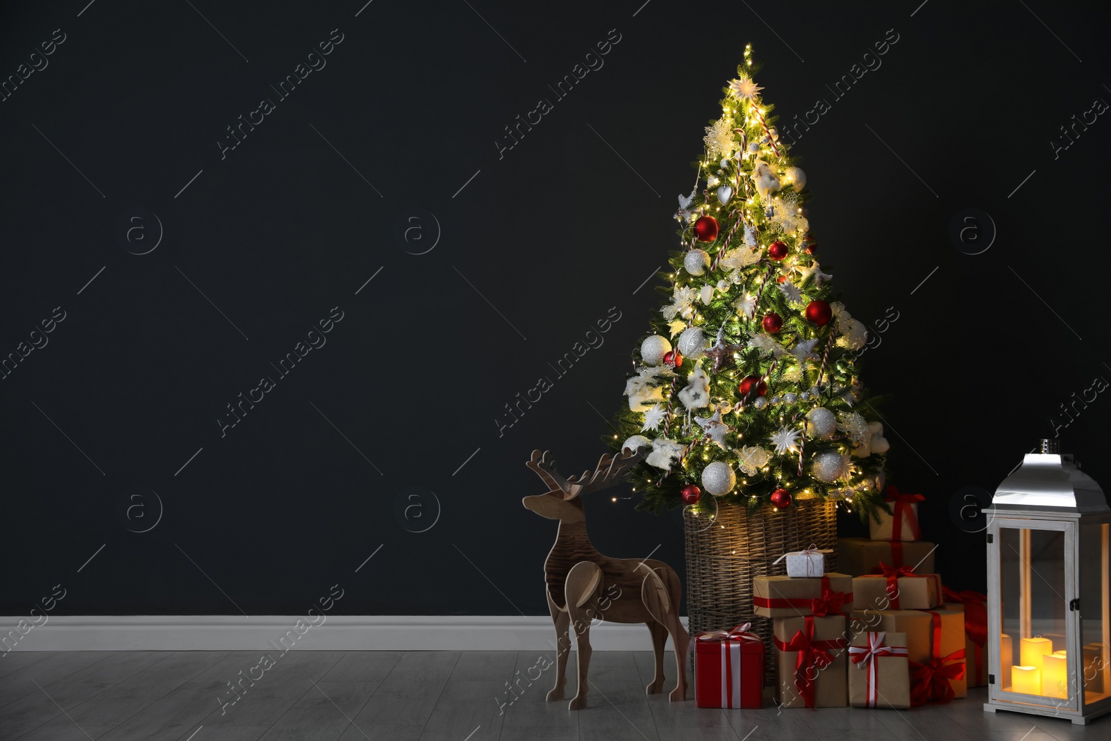 Photo of Beautiful Christmas tree, festive decor and gift boxes near black wall indoors, space for text