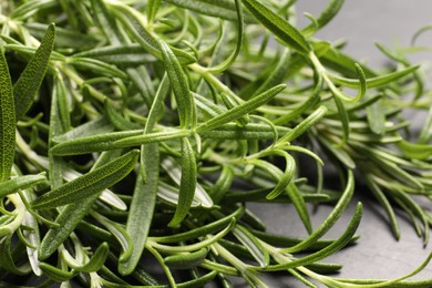 Photo of Aromatic green rosemary sprigs on gray table, closeup