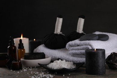 Composition with different spa products and burning candles on grey textured table