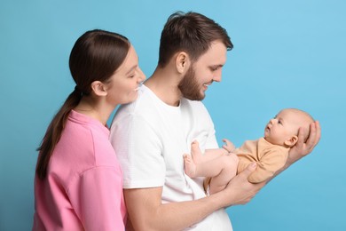 Photo of Happy family. Parents with their cute baby on light blue background