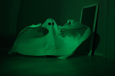 Creepy ghost. Woman covered with sheet in green light