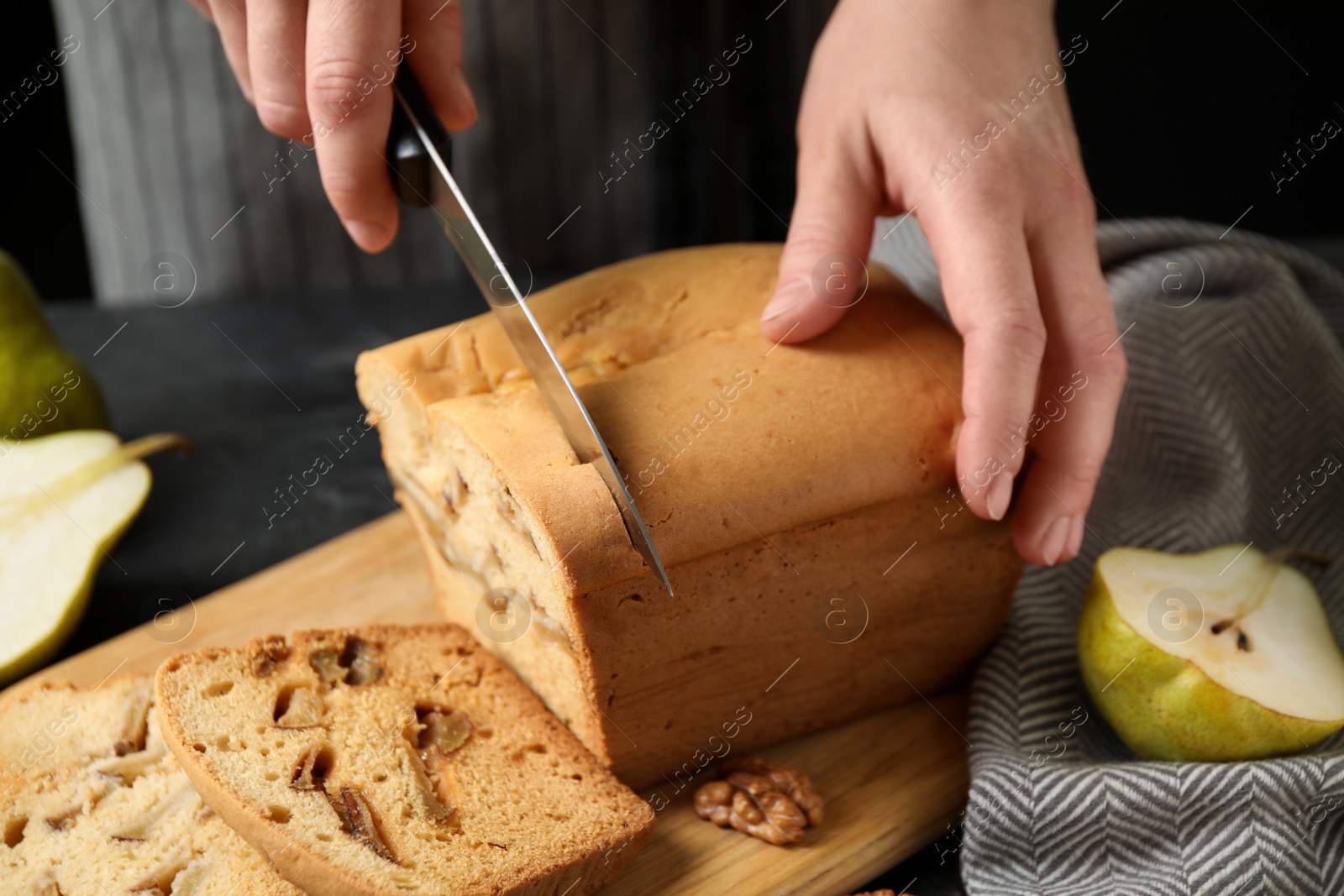 Photo of Woman cutting pear bread at table, closeup. Homemade cake