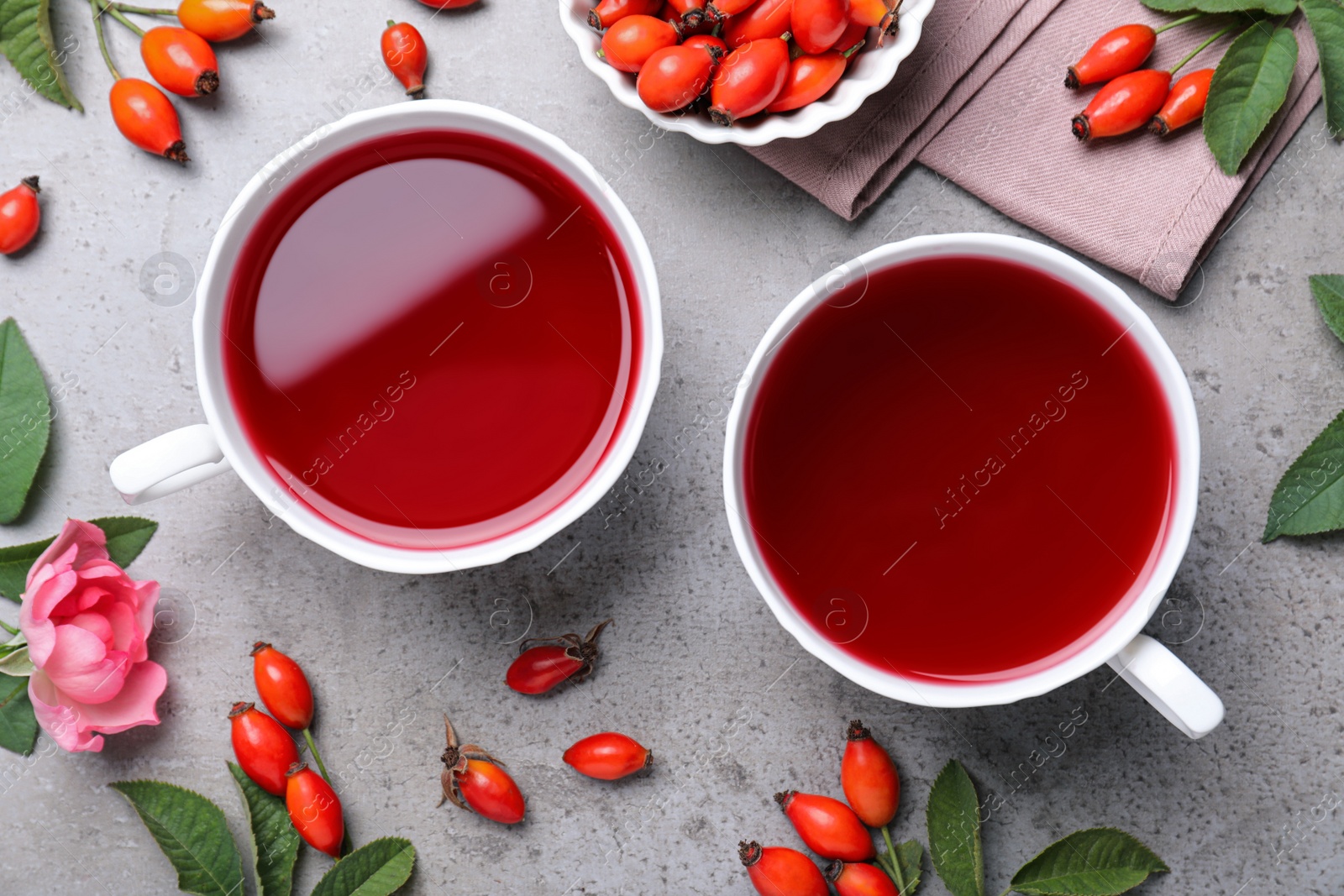 Photo of Fresh rose hip tea and berries on grey table, flat lay