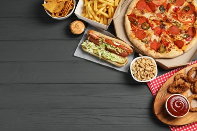 French fries, onion rings and other fast food on gray wooden table, flat lay with space for text