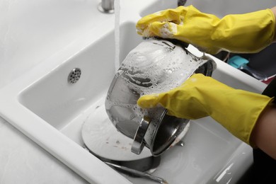 Photo of Woman washing dirty dishes in kitchen sink, closeup