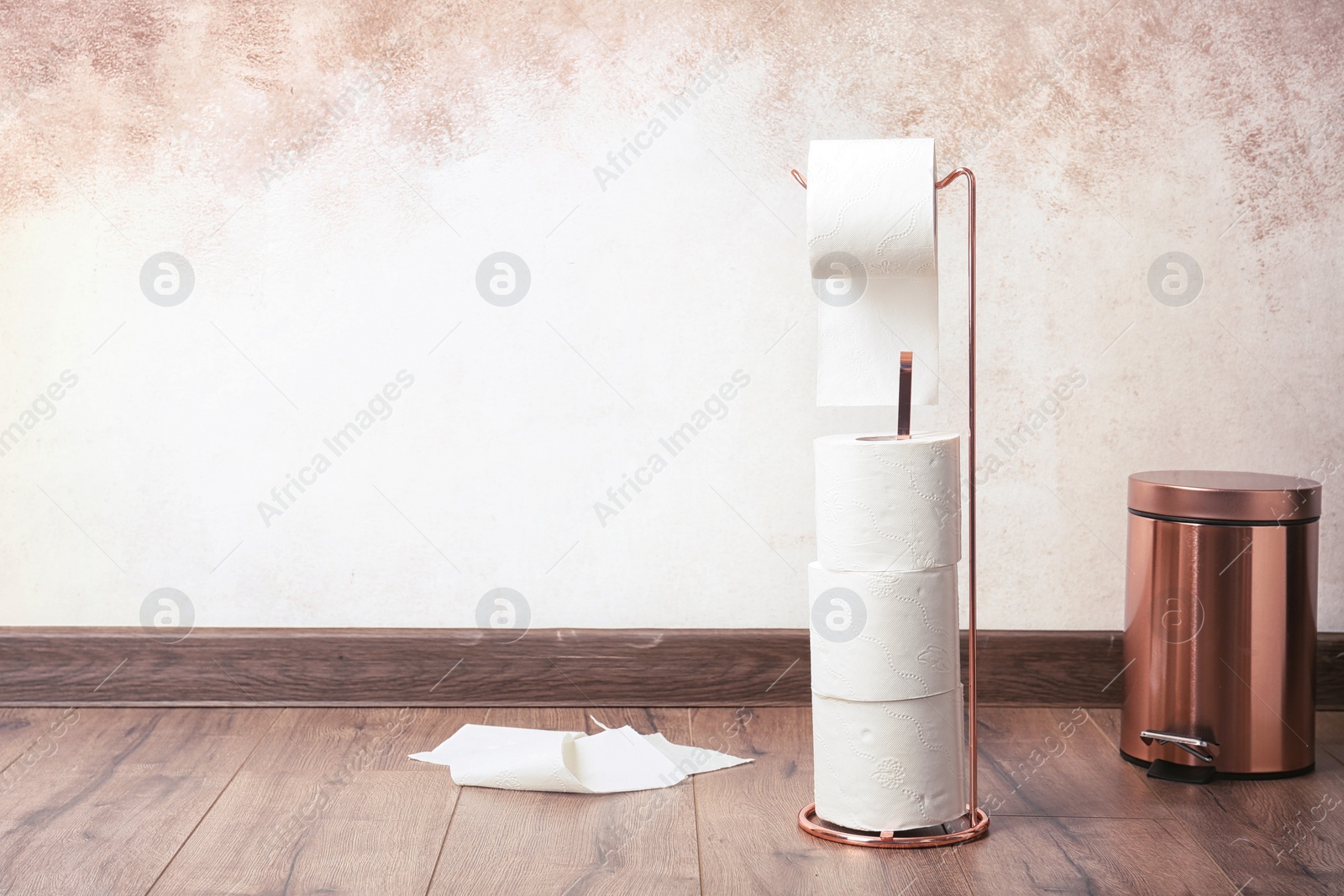 Photo of Toilet paper holder with rolls on floor indoors. Space for text