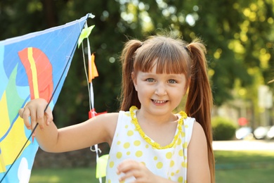 Cute little girl with kite in green park on sunny day. Happy child