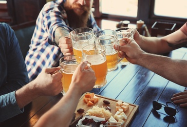 Photo of Friends clinking glasses with beer in pub
