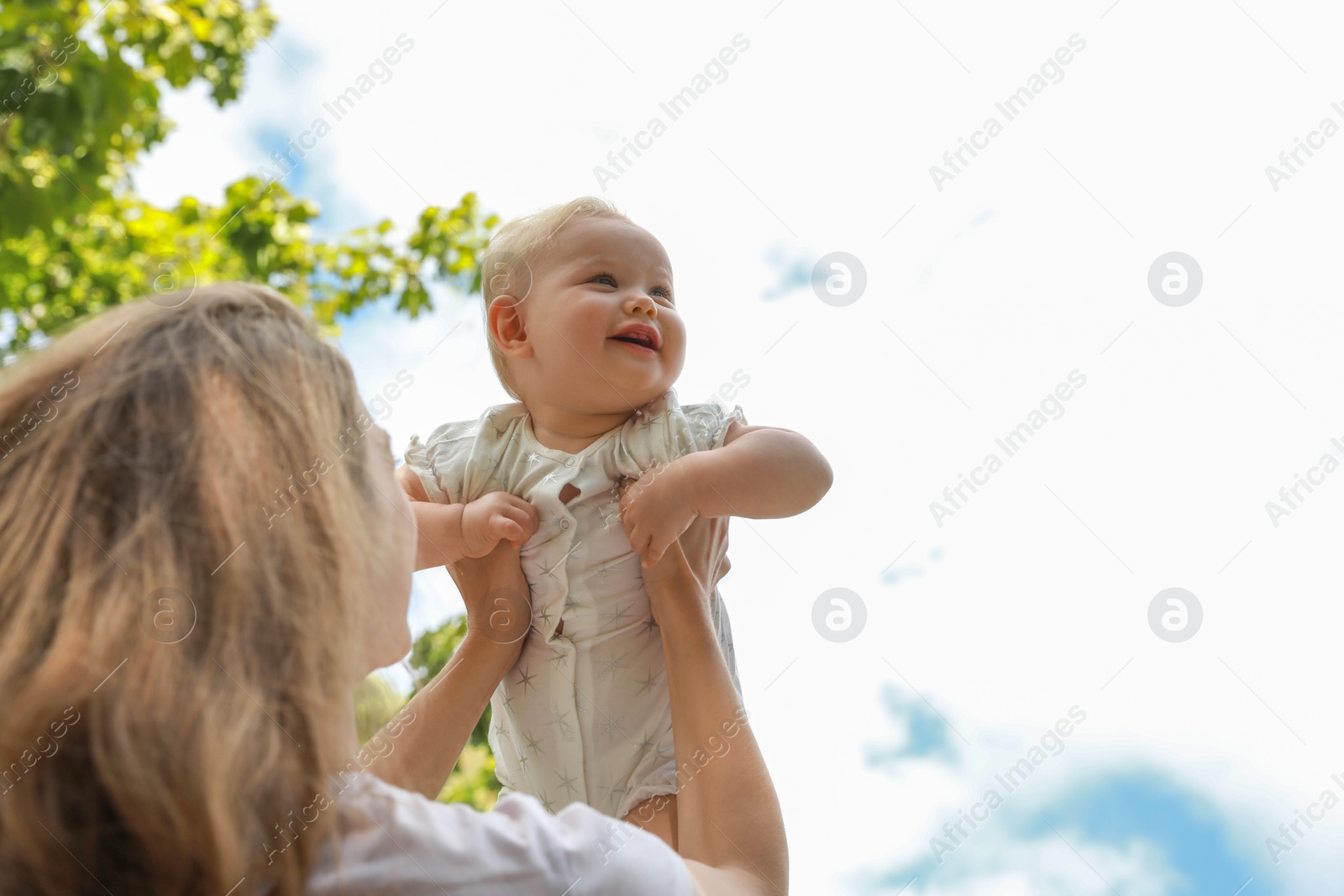 Photo of Mother with her cute baby spending time together outdoors, low angle view. Space for text