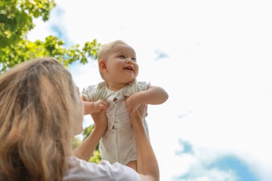 Photo of Mother with her cute baby spending time together outdoors, low angle view. Space for text