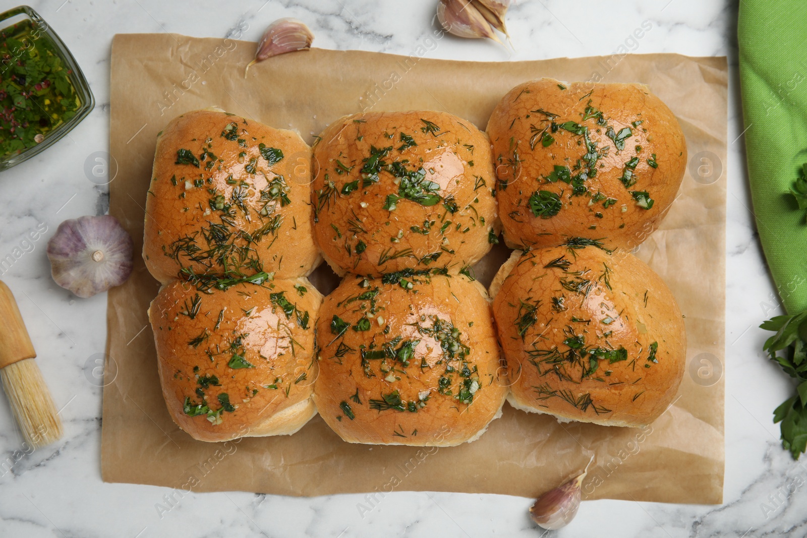 Photo of Traditional pampushka buns with garlic and herbs on white marble table, flat lay