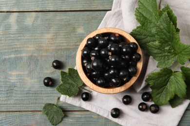 Ripe blackcurrants and leaves on wooden rustic table, flat lay. Space for text