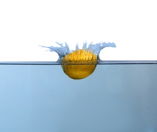 Photo of Ripe lemon falling down into clear water with splashes against white background