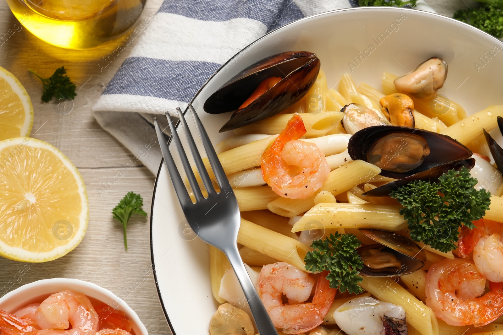 Photo of Delicious pasta with sea food served on white wooden table, flat lay