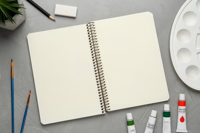 Flat lay composition with blank sketchbook on light grey stone table. Space for text