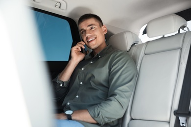 Photo of Attractive young man talking on phone in luxury car