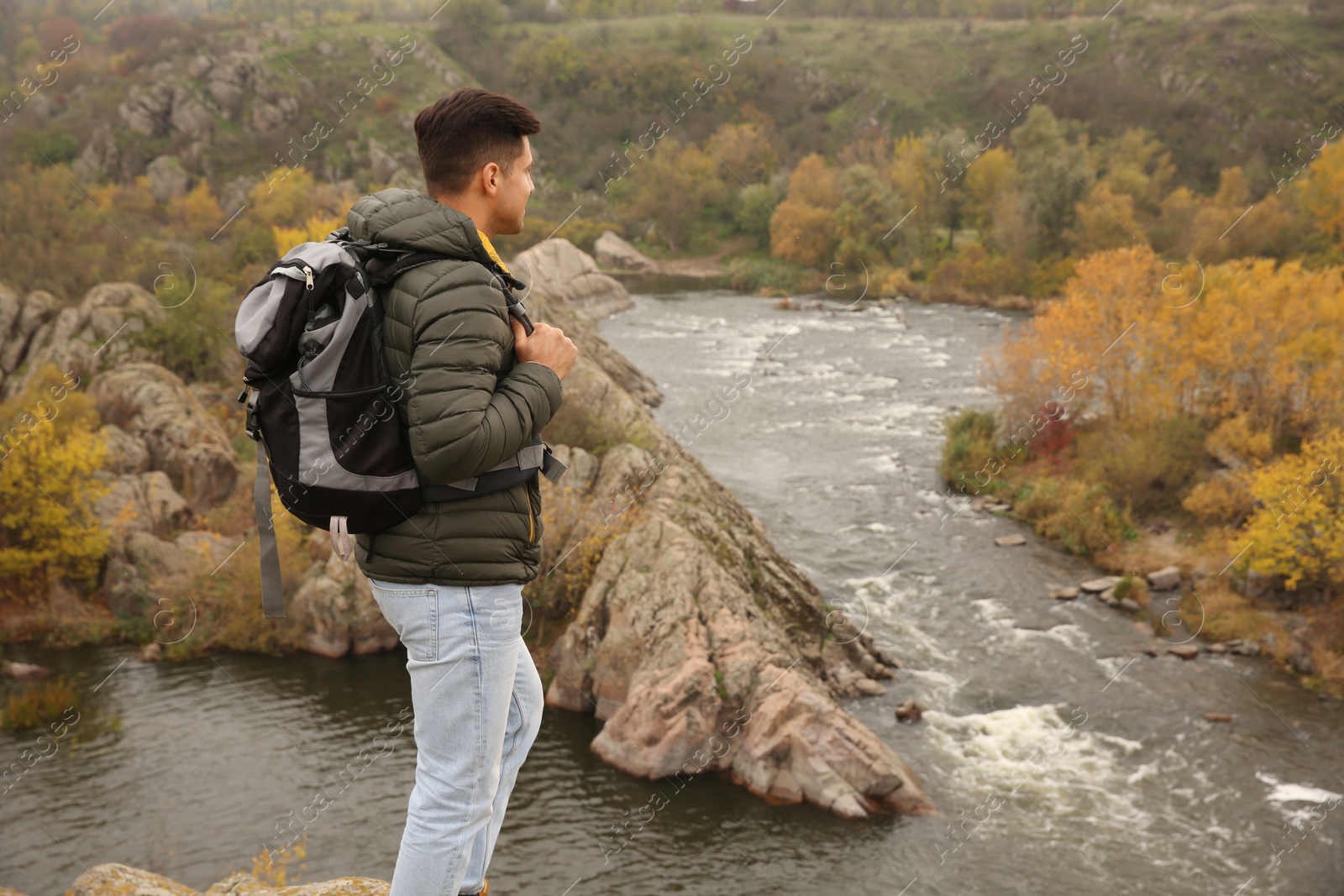 Photo of Man with travel backpack enjoying nature near mountain river