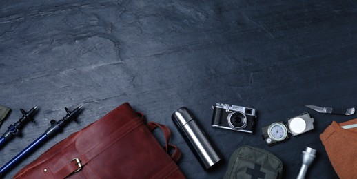 Photo of Flat lay composition with leather tourist backpack and camping equipment on black background, space for text