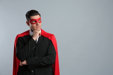 Photo of Businessman wearing superhero cape and mask on grey background. Space for text