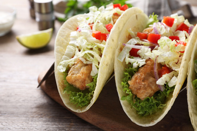 Photo of Yummy fish tacos served on wooden table, closeup