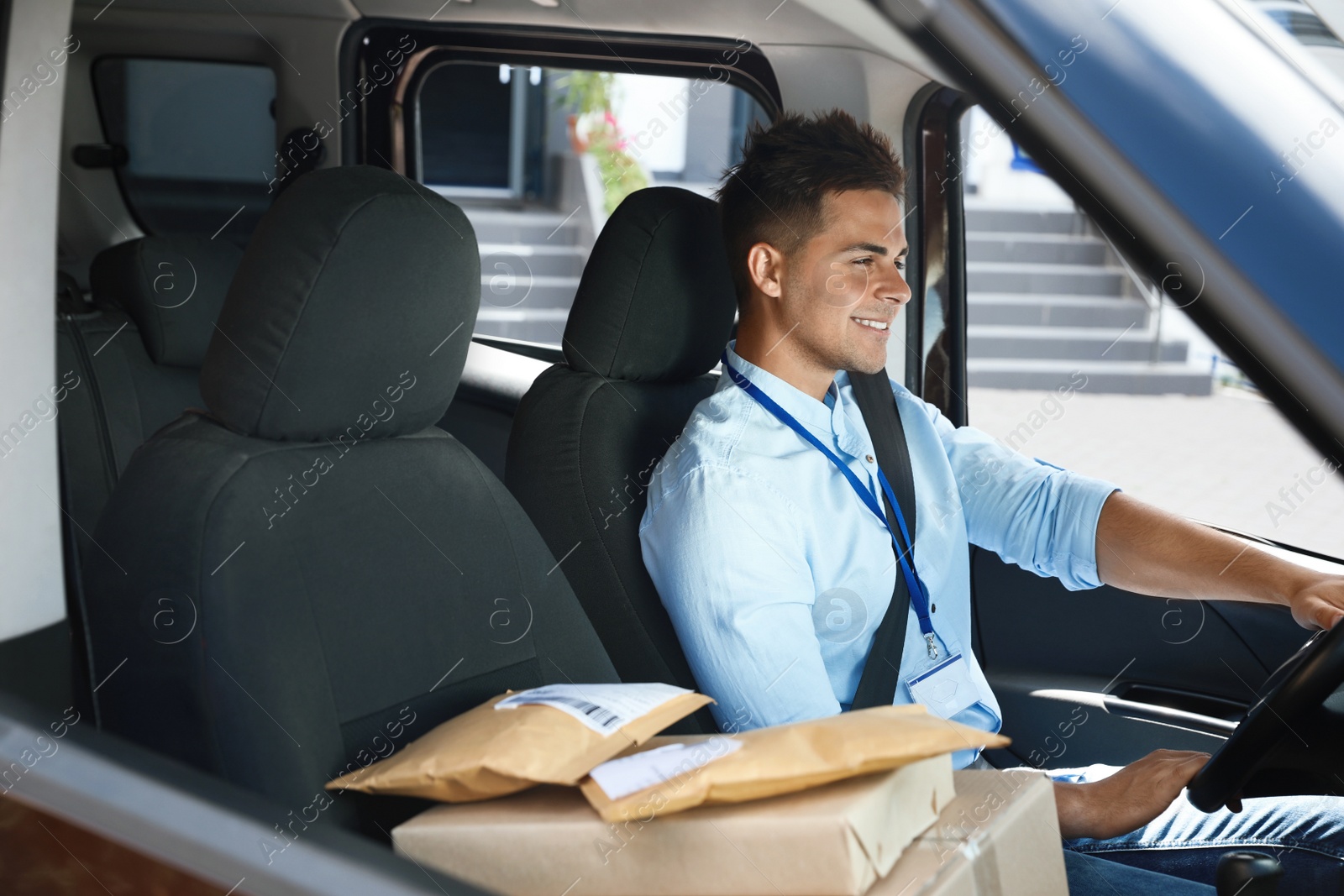 Photo of Young courier with parcels in delivery car