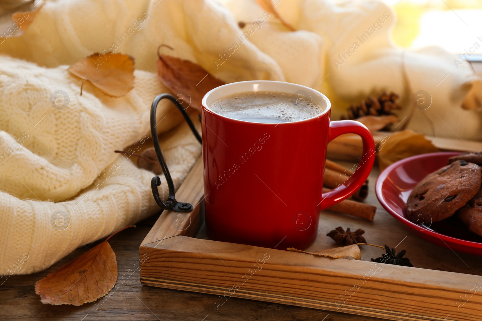 Photo of Composition with cup of hot drink, sweater and autumn leaves on windowsill. Cozy atmosphere