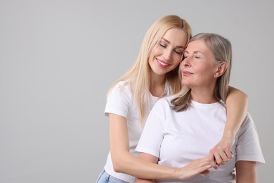 Photo of Family portrait of young woman and her mother on light grey background. Space for text