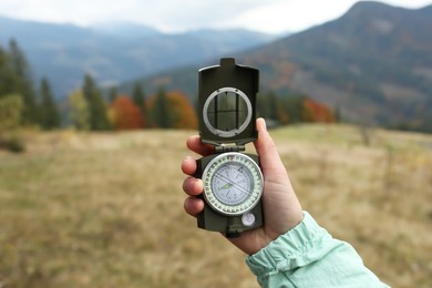 Photo of Woman using compass during journey in mountains, closeup