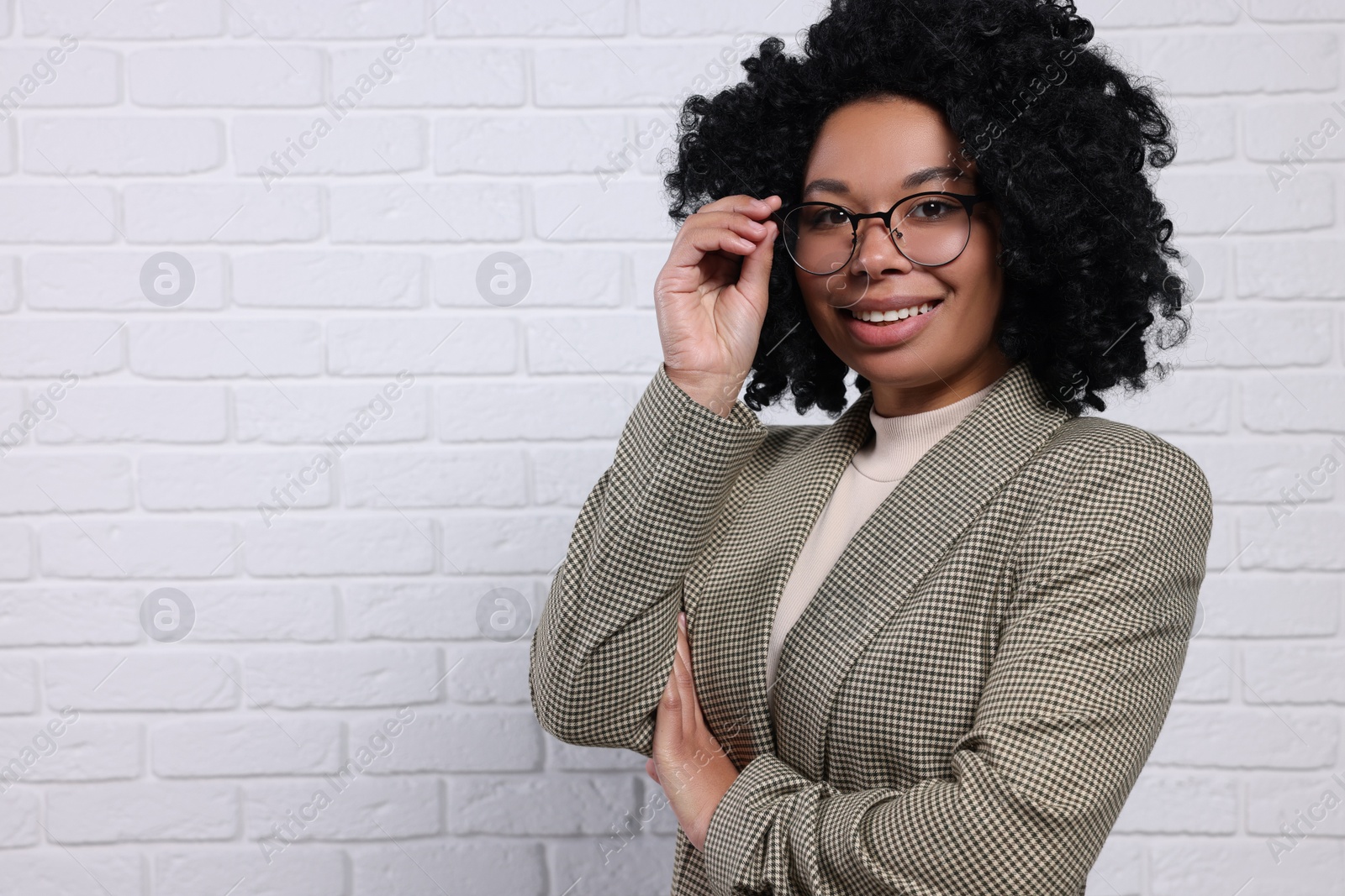 Photo of Young businesswoman in eyeglasses near white brick wall. Space for text