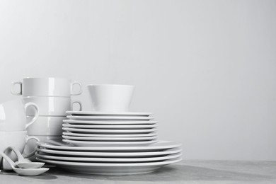 Photo of Set of clean dishware on grey table against light background. Space for text