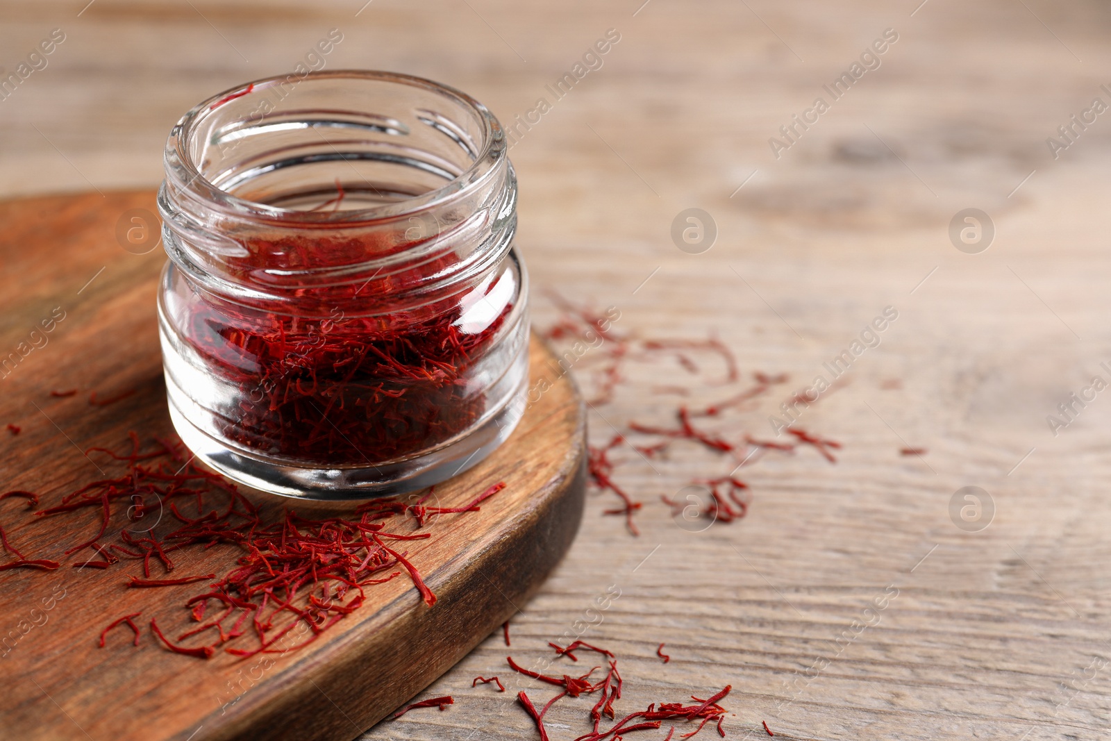 Photo of Aromatic saffron in glass jar on table, space for text