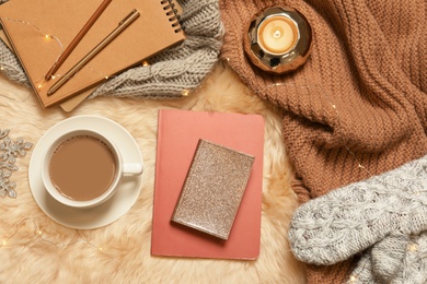 Photo of Flat lay composition with notebooks, cup of coffee and warm blankets on fuzzy rug