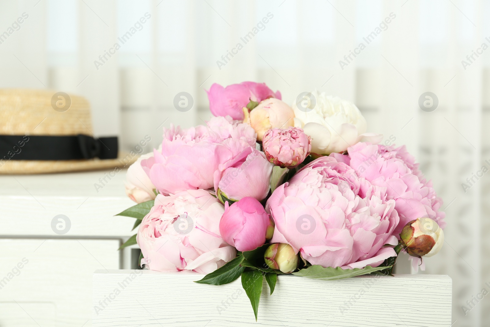 Photo of Bouquet of beautiful peonies in commode drawer indoors