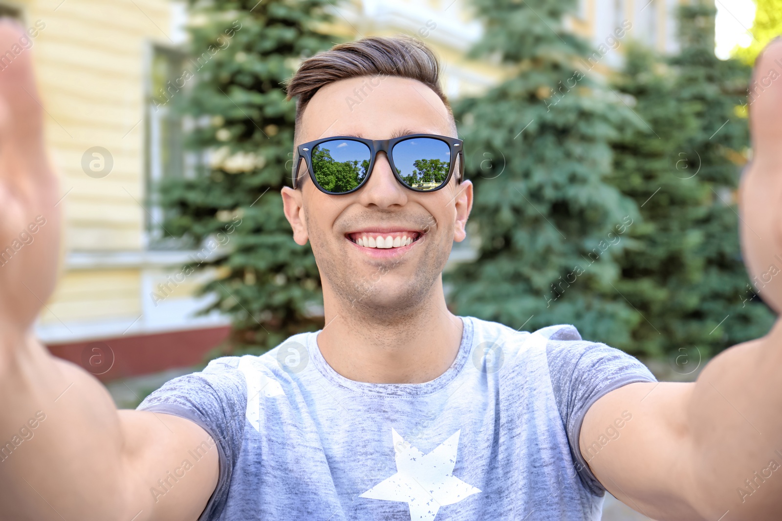 Photo of Young man in sunglasses taking selfie outdoors