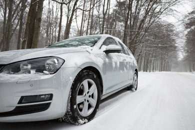 Photo of Car with winter tires on snowy road in forest, space for text